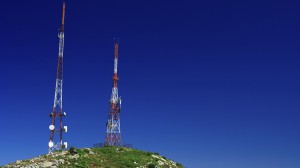 Telecommunication tower on the green field with blue sky