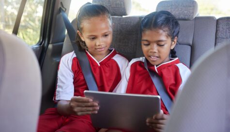 Children, friends and tablet in car entertainment, online streaming or social media. Kids enjoying games or apps while relaxing in seat on touchscreen